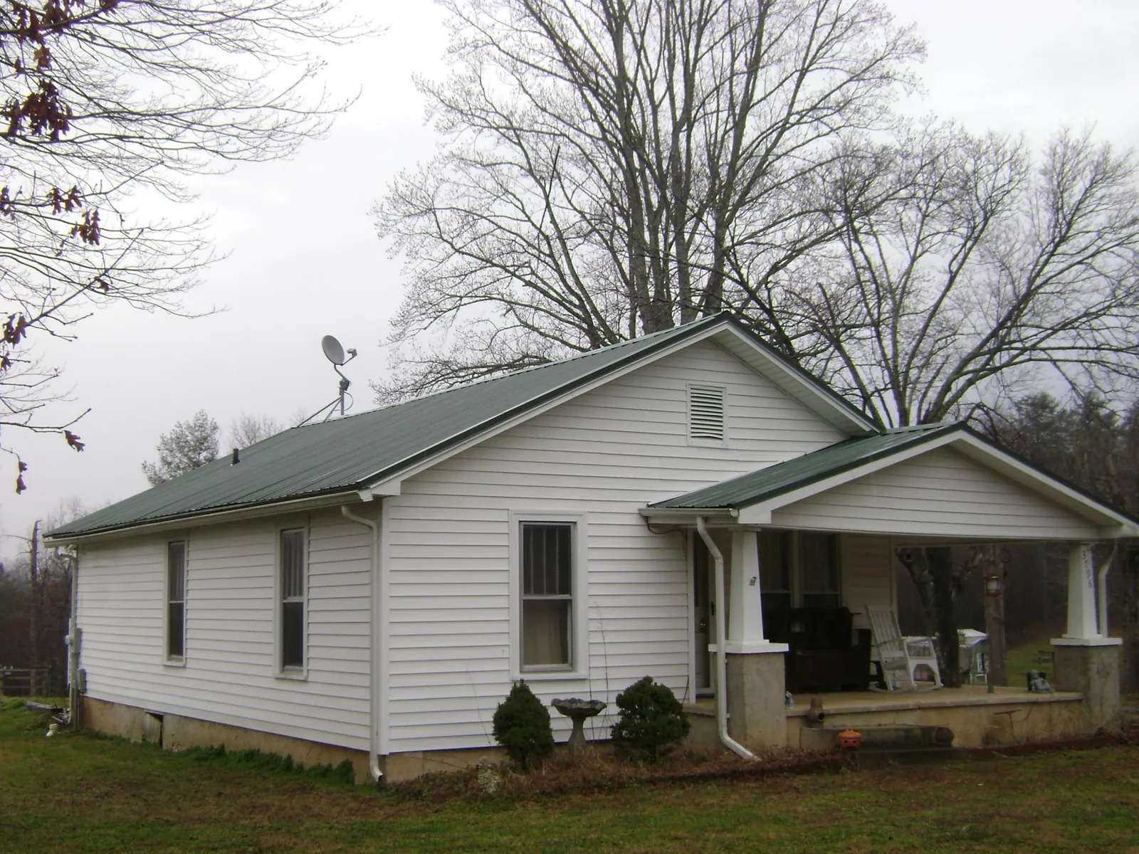 Green metal roof on a white bungalow with a side porch in Cordova
